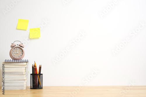 Office desk with pencils, alarm clock and book on wood table. work copy space. photo