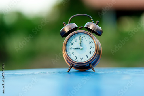 Golden alarm clock picture placed on a blue table, green background Punctual concept With copy space