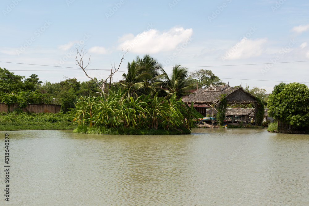 Small tropical island with palm trees in the middle of the Asian river in the city.