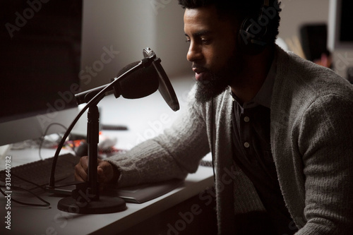 Bearded businessman talking over microphone in recording studio