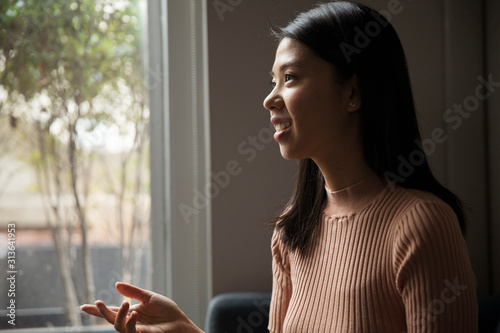 Free Download Side view of smiling businesswoman talking while sitting against window in office - GFXLoad