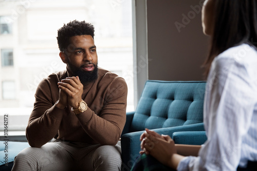 Business people discussing while sitting against window in creative office