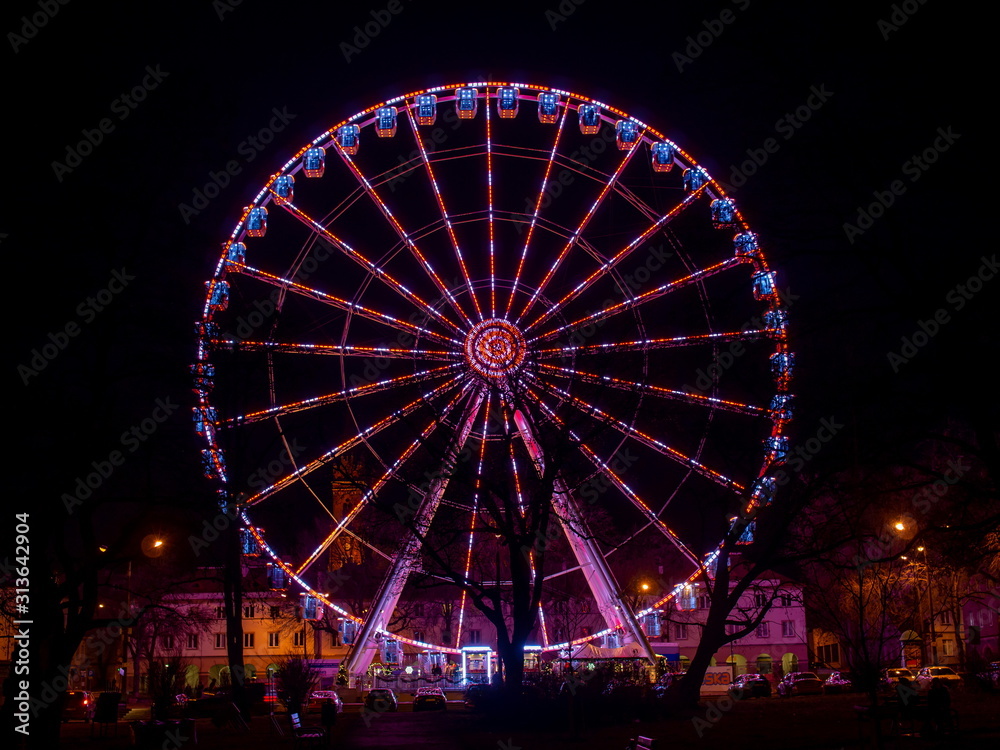 Red tone illuminated colorful illuminated ferris wheel at night
