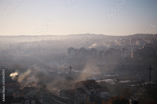 Winter morning atmosphere view on landscape of houses and buildings with fog covered street. Environmental disaster. Harmful emissions and exhaust gases into air. Winter day, weather, heating season.