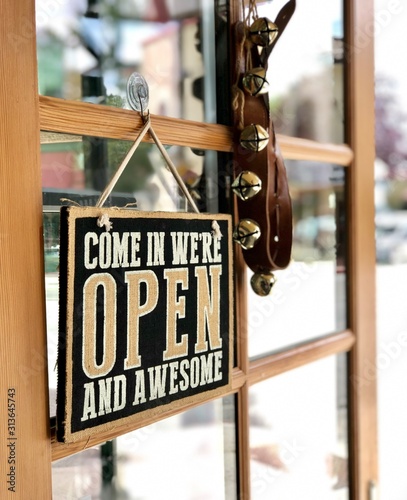 Come in we are open sign and bells are hanging on the door of a small retail business