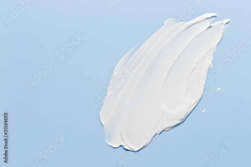 Fotografia White cosmetic cream lotion moisturizer strokes on pastel blue