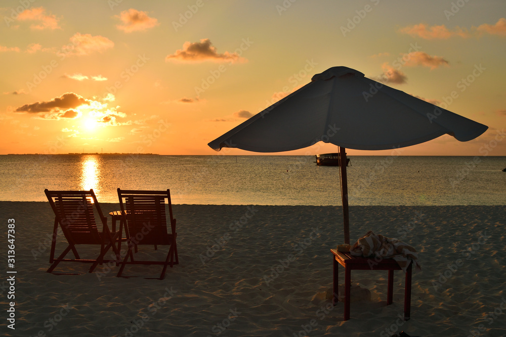 View of umbrella and sunbeds facing the Indian Ocean and the beautiful sunset.