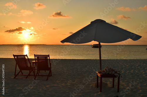 View of umbrella and sunbeds facing the Indian Ocean and the beautiful sunset.