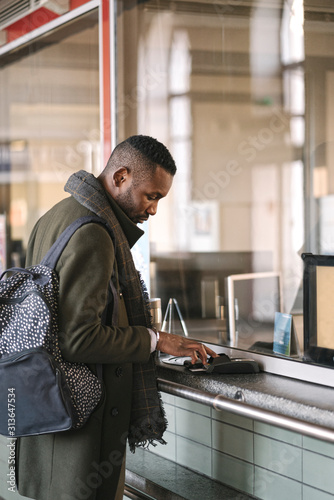 Stylish man buying ticket in train station