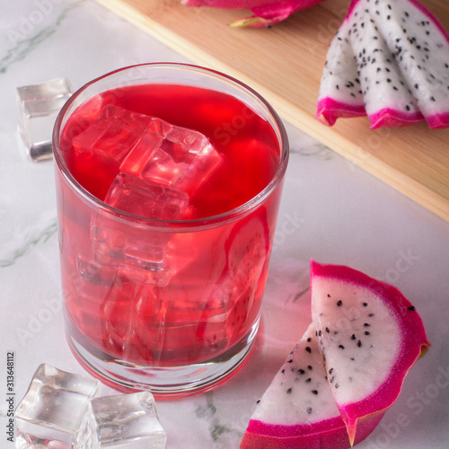Tableau sur toile Glass of mango dragonfruit refresher drink on marble table with ice cubes
