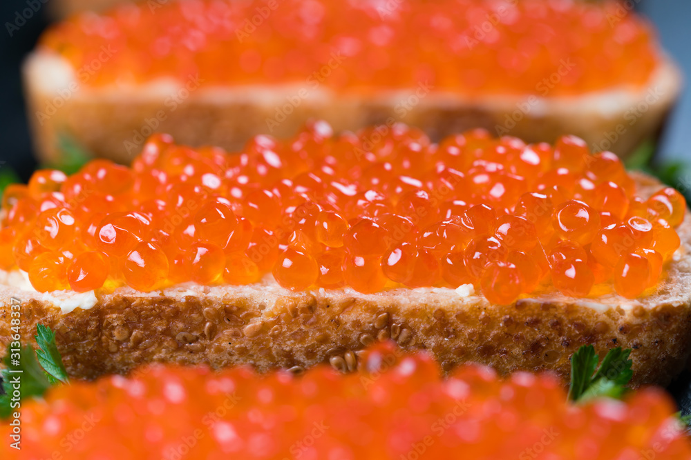 Sandwiches with red caviar on dark stone background