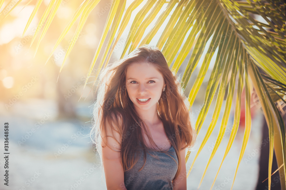 portrait face of a beautiful young girl sunbathing in the sun on the beach paradise looks with one eye wink and squinting at a very bright sunny warm day and smiling portrait face of a beautiful young girl sunbathing in the sun on the beach paradise looks with one eye wink and squinting at a very bright sunny warm day and smiling