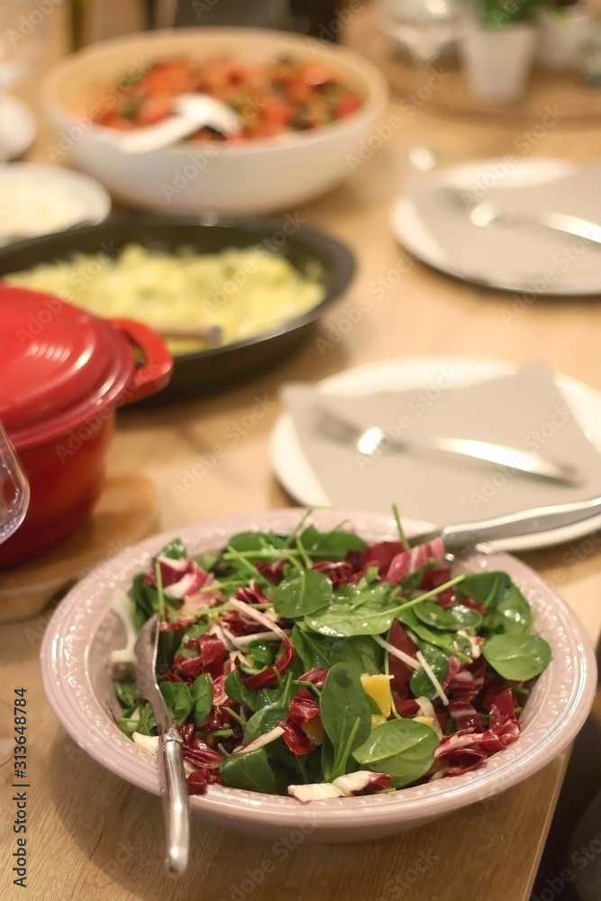 Spinach, chicory, fennel and orange salad served on the festive table setting. Selective focus. Spinach, chicory, fennel and orange salad served on the festive table setting. Selective focus.