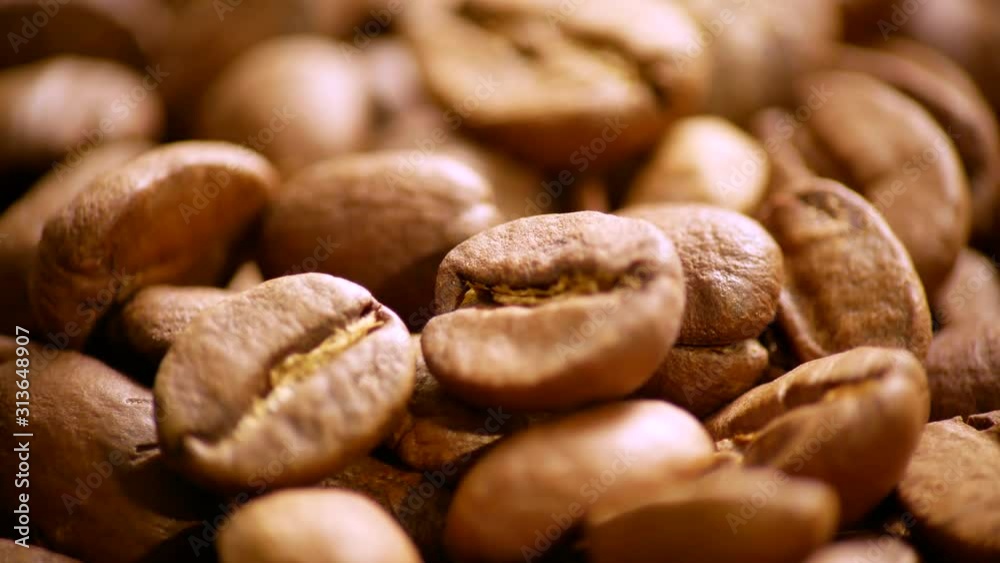 Fragrant coffee beans are roasted in a frying pan. The composition scrolls slowly around the camera. Macro shot. Fragrant coffee beans are roasted in a frying pan. The composition scrolls slowly around the camera. Macro shot.