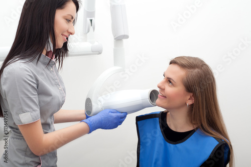 The dentist makes an x-ray of the patient's teeth, the girl doctor on a white background, with an x-ray machine and the patient. The concept of treatment of the teeth or health of the oral cavity.