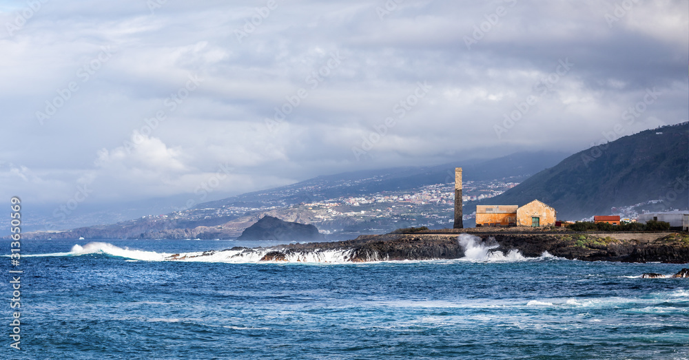 Large waves crashingon the rocks near an old sugar Mill chimney near Los Silos, Tenerife, Spain on 21 November 2019