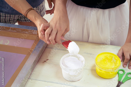 White paint shovel in women's and children's hands in creativity room. Master class on art for children.
