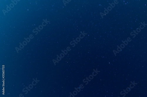 Moving stars at night, dark blue sky background. Long exposure shot. 