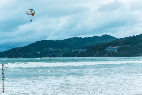 Thailand - July, 2019: skydiver flies through the sky over the sea Kata beach