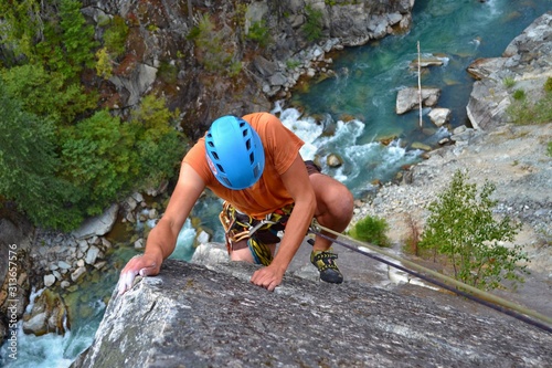 Climbing the majestic Star Chek multi-pitch route just south of Whistler. Young man is climbing beautiful climbing route above the wild river.