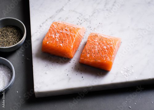 Close up of salmon pieces with salt and pepper on marble board