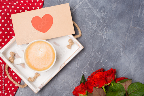 Close-up. Valentine's Day concept. Morning coffee, envelope with heart, roses on grey desk. Free space. Space for text. 