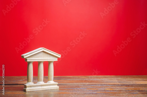 Government or court building on a red background. Building figurine with pillars in antique style. Concept of city administration, bank, university or library. Architectural monument