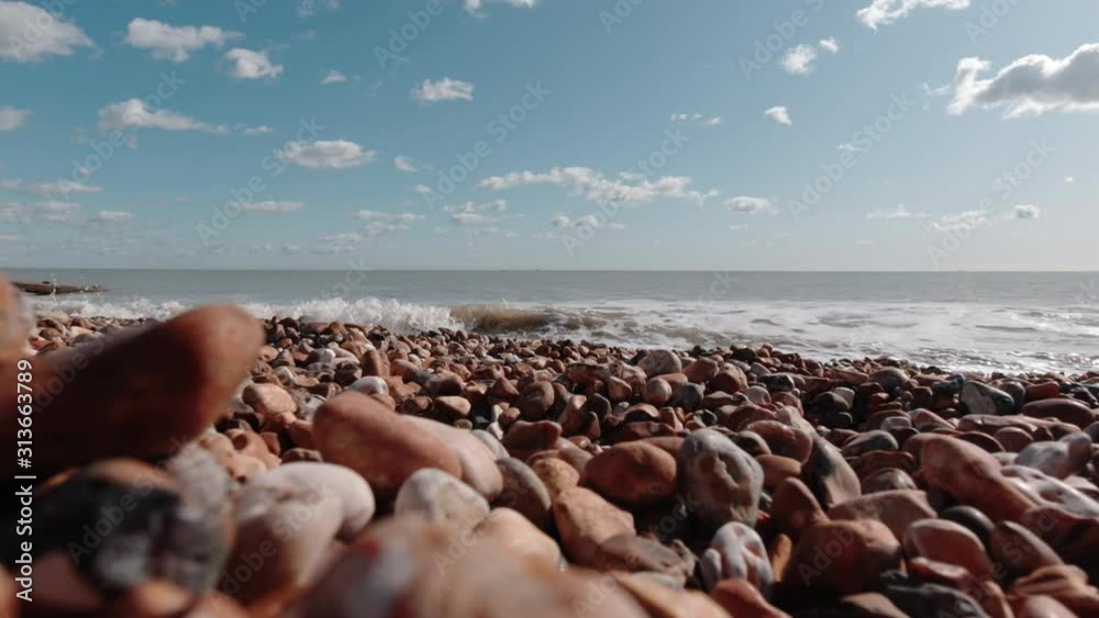 Close up of pebble stone beach in Pevensey,south England on a sunny day while waves crashing gently to the shore Close up of pebble stone beach in Pevensey,south England on a sunny day while waves crashing gently to the shore