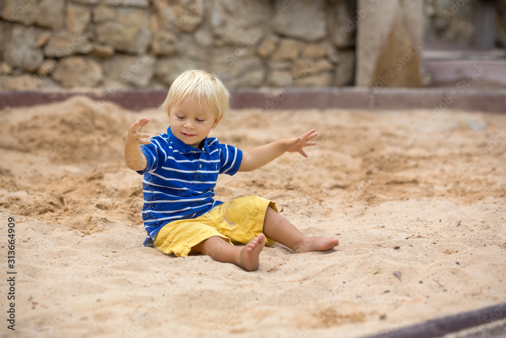 Little toddler boy, playing with sand in sandpit at the playground Little toddler boy, playing with sand in sandpit at the playground