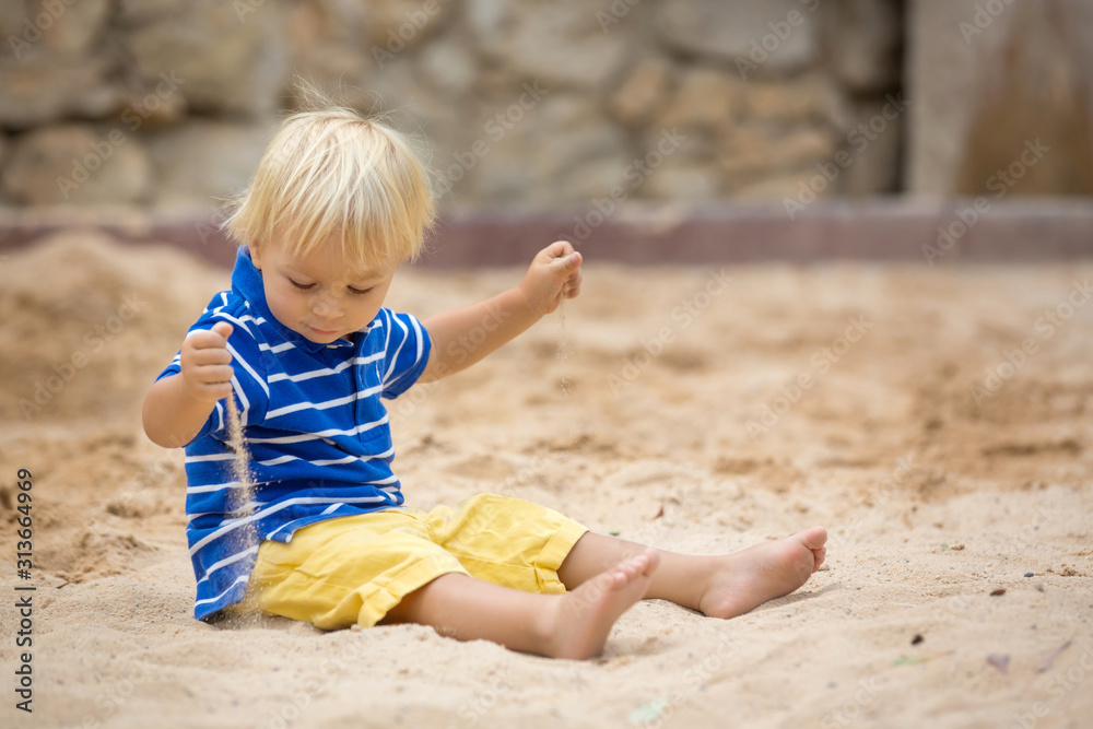 Little toddler boy, playing with sand in sandpit at the playground Little toddler boy, playing with sand in sandpit at the playground
