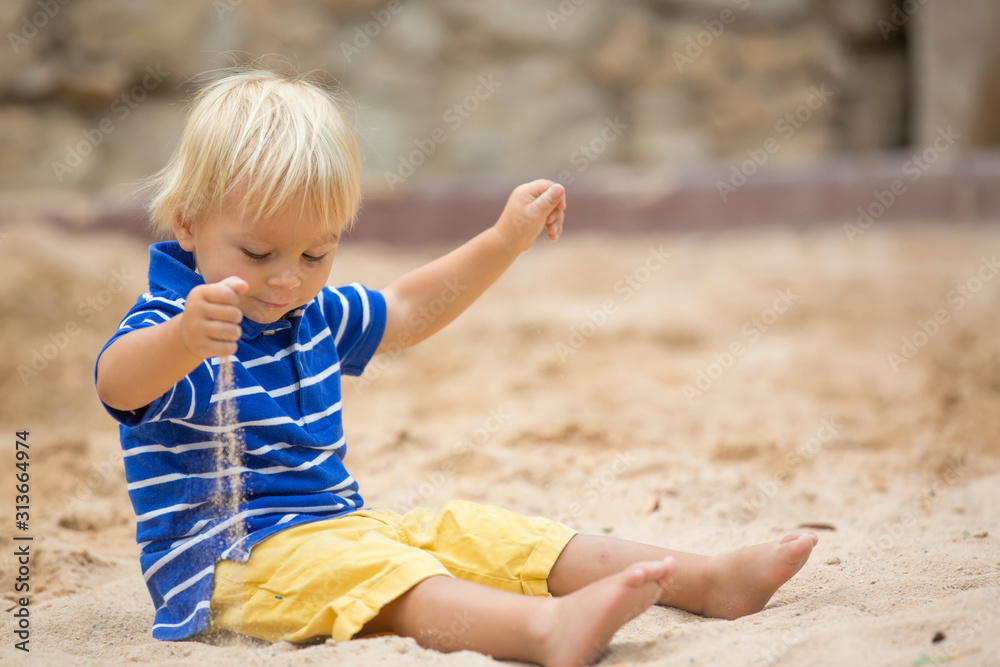 Little toddler boy, playing with sand in sandpit at the playground Little toddler boy, playing with sand in sandpit at the playground