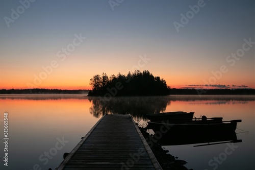 lake with jetty and row boat at dawn