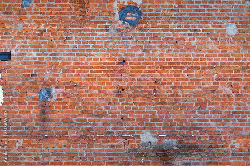 an old red brick wall taken down on a cloudy winter day