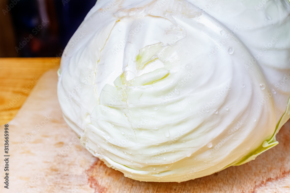 Whole head of fresh white cabbage with water drops on the wooden cutting board Whole head of fresh white cabbage with water drops on the wooden cutting board