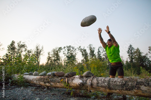 Strong man throws large rock during an outdoor workout.