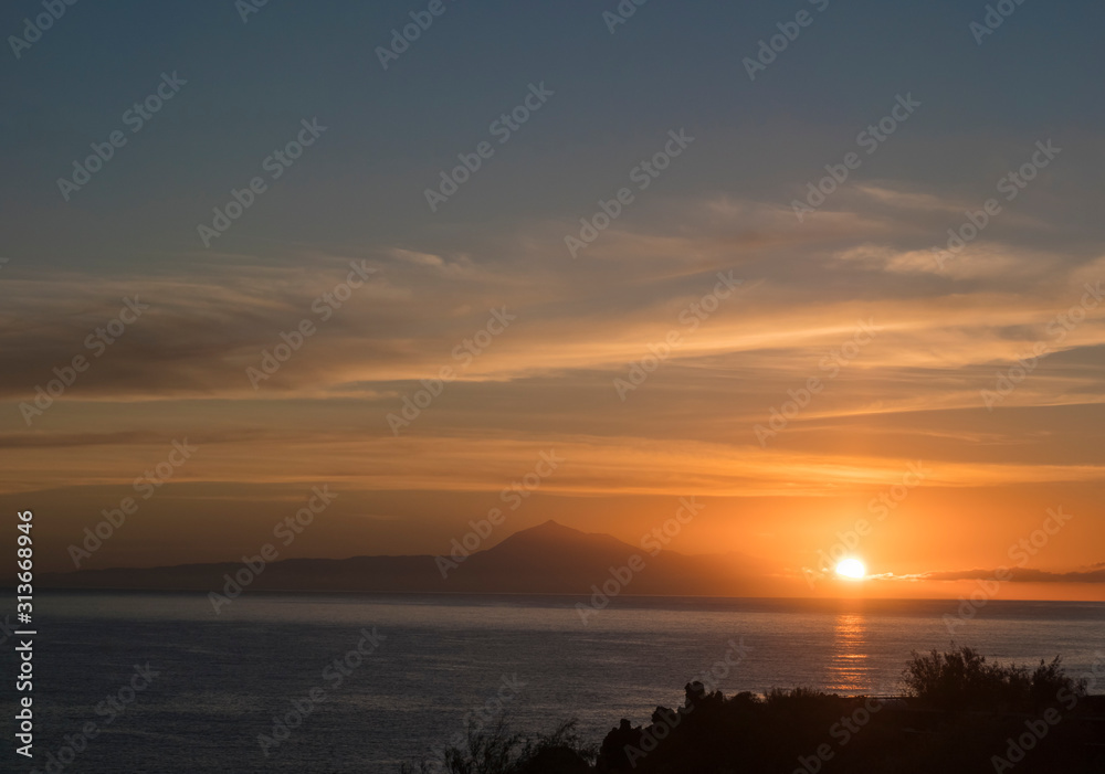 Beautiful orange sunrise over calm ocean and mountain pico del Teide at Tenerife seen from La Palma, Canary Island