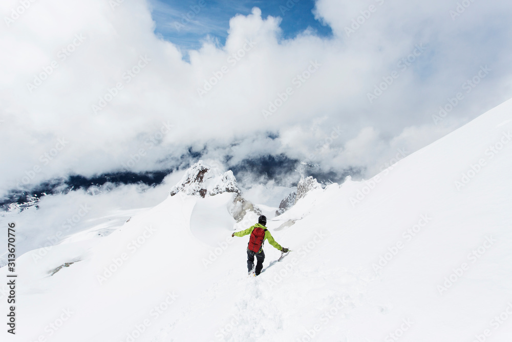 A young man descends from the summit of Mt. Hood on a cloudy day. A young man descends from the summit of Mt. Hood on a cloudy day.