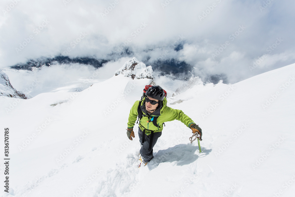 A young man climbs to the summit of Mt. Hood in Oregon on a cloudy day A young man climbs to the summit of Mt. Hood in Oregon on a cloudy day