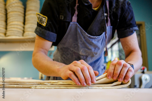 Close-up view of a baker folding buttered pastry dough on a countertop