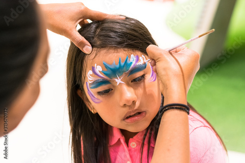 Girl painting her face like a princess by face painting artist photo