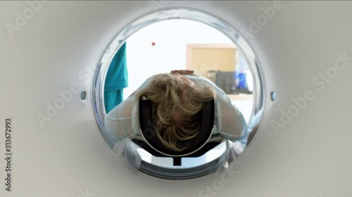 Close-up shot of a female mature patient lying on a table of CT scan machine. Computer tomograph scanning body and brain of elderly woman. High-tech equipment in medical clinic. 4K