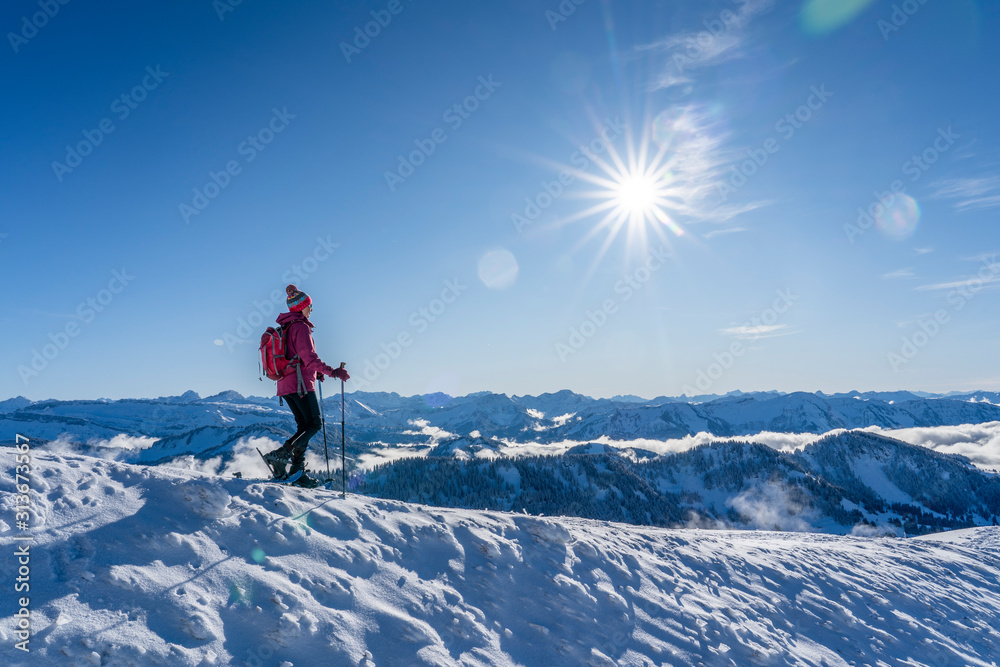 nice senior woman snowshoeing on the Nagelfluh chain above a sea of fog over Bregenz Wald mountains, Hochgrat, Steibis,Bavarian alps, 