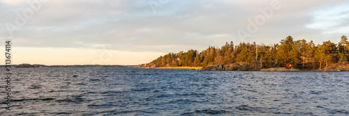 Seascape. Sunset background. Islands with pines in the rays of the setting sun. Stockholm Archipelago. Scandinavia. Seaside. Horizon line, skyline with beautiful clouds. Header.