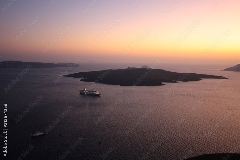 View of the island of Nea Kameni, the sea and the caldera of Santorini at sunset