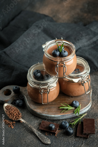 Chocolate mousse in glass jar with berries on a dark background copy space. Homemade dessert.