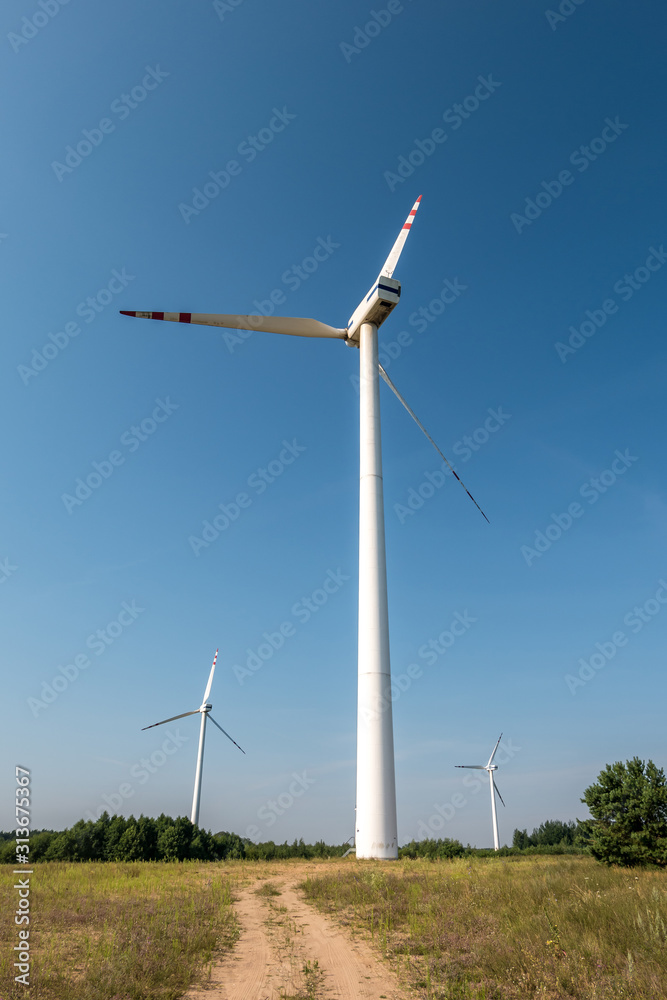 rotating blades of a windmill propeller on blue sky background. Wind power generation. Pure green energy.