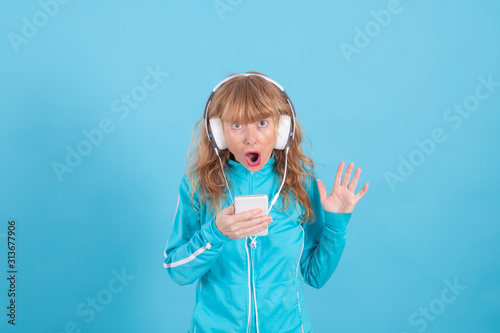 adult woman wearing sportswear with headphones and mobile phone isolated on color background