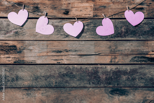 Old wooden background with a garland of pink hearts. Natural rope and clothespins. Concept of recognition of love, romantic relationships, Valentine's day in grunge style. Copy space