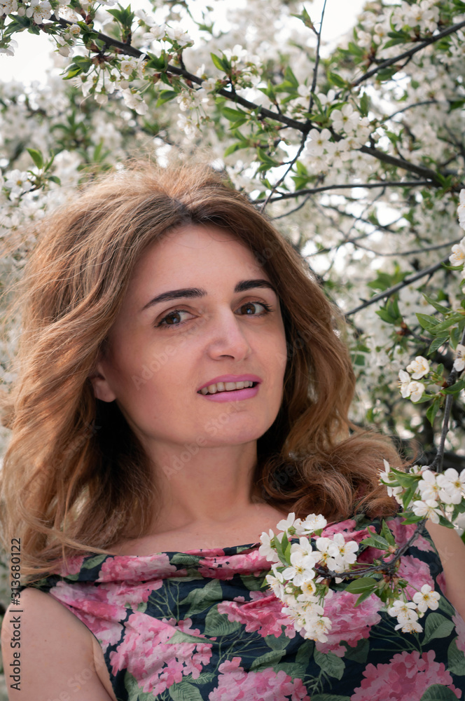 soft focus of smiling woman with long hair in pink and black dress near cherry tree with beautiful white blossom in garden soft focus of smiling woman with long hair in pink and black dress near cherry tree with beautiful white blossom in garden