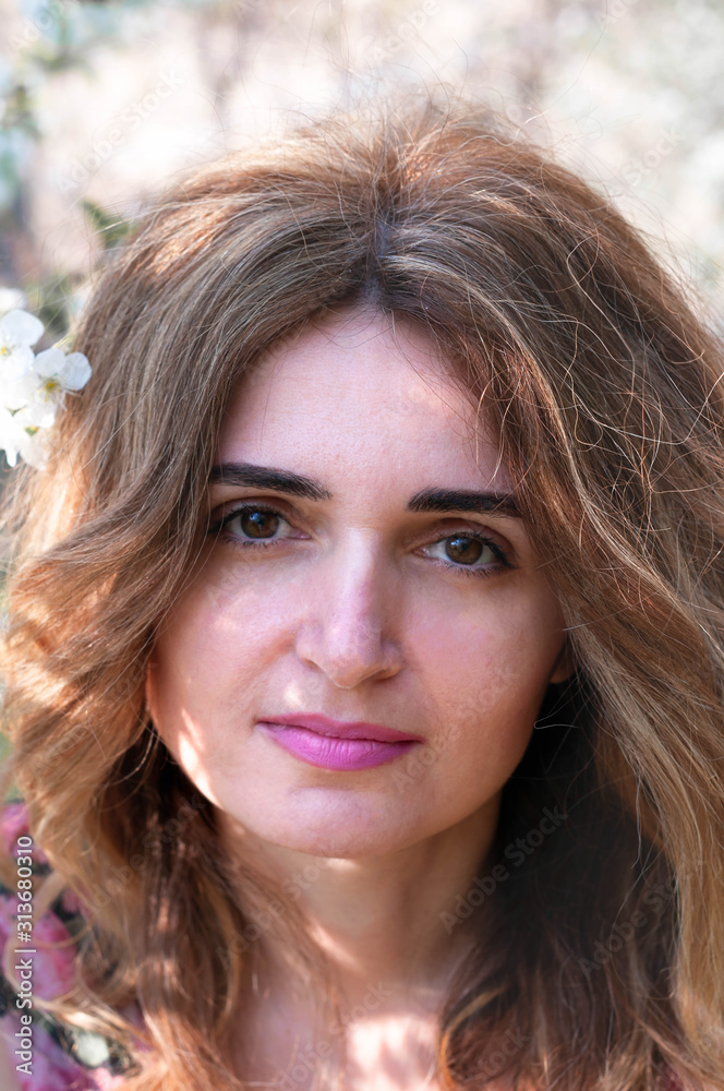soft focus of portrait of attractive and confident woman with white cherry flowers in long hair looking at camera in front of blossoming branches in garden with sunshine soft focus of portrait of attractive and confident woman with white cherry flowers in long hair looking at camera in front of blossoming branches in garden with sunshine